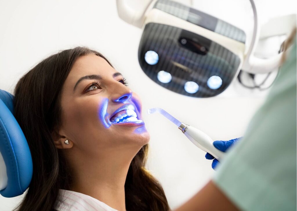 Professional teeth whitening treatment using a whitening light in a dental office, demonstrating one option compared to teeth whitening strips effectiveness.